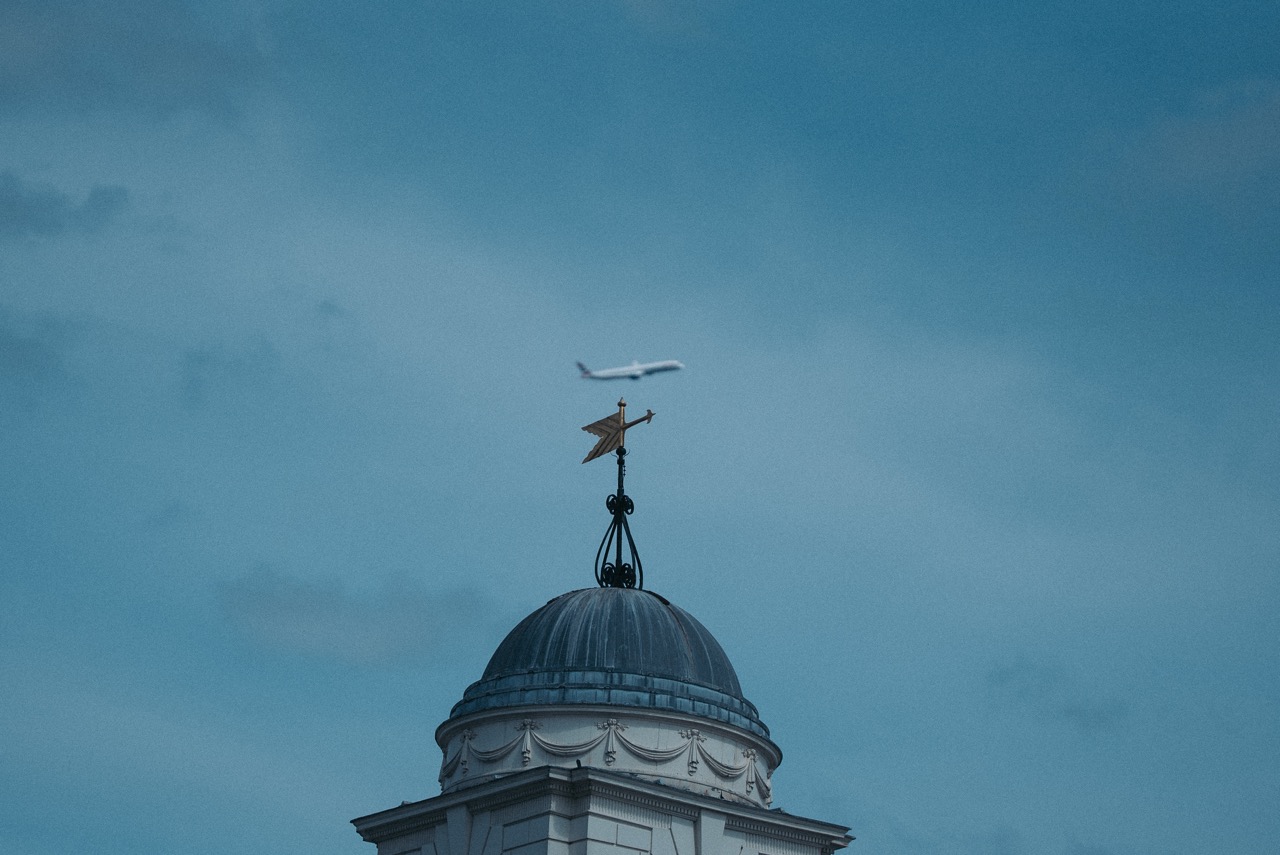 Cata-vento dourado e avião no céu