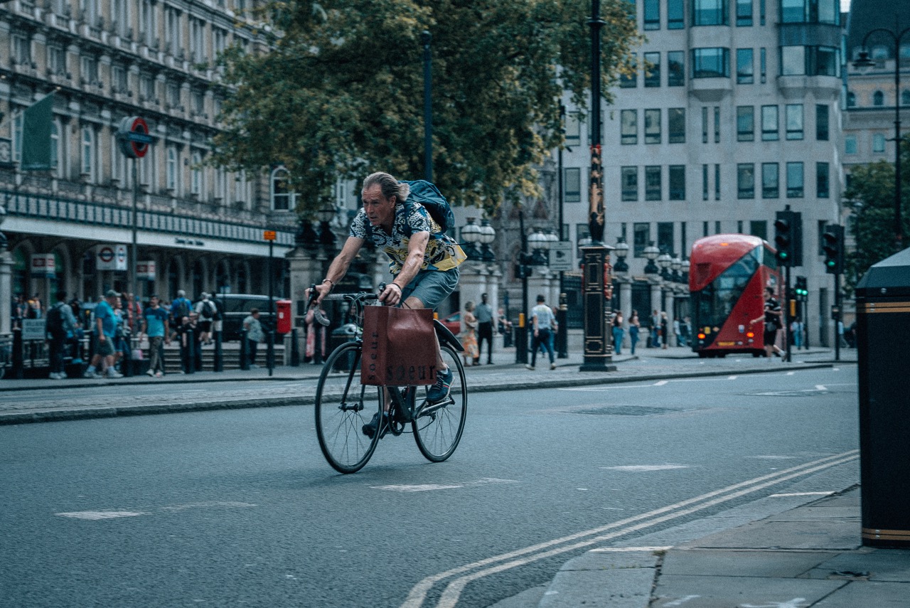 Ciclista cruzando Trafalgar — ônibus vermelho ao fundo