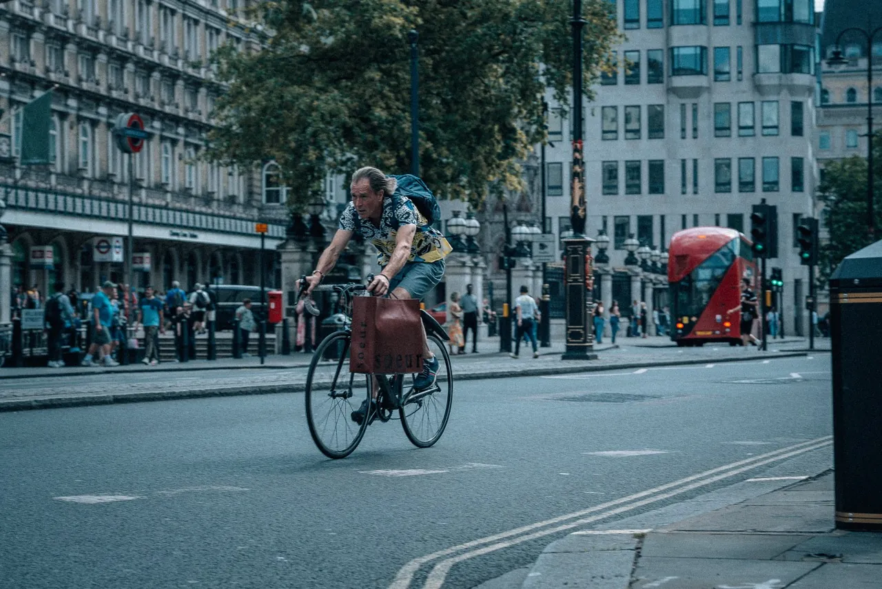 Ciclista cruzando Trafalgar — ônibus vermelho ao fundo