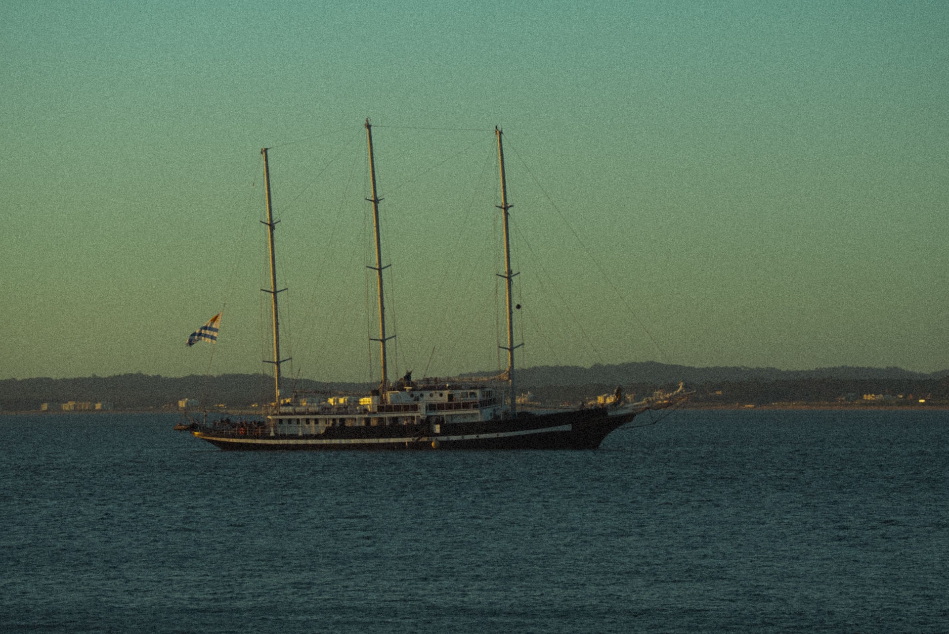 Veleiro com bandeira uruguaia ao entardecer