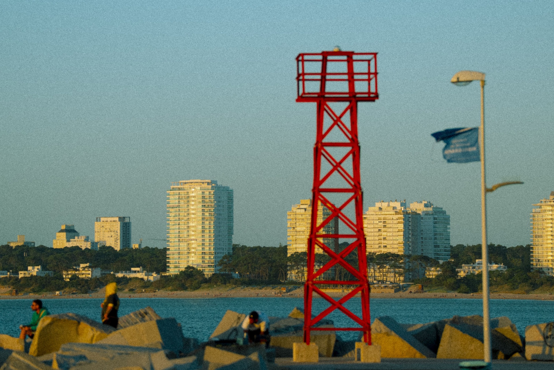 Torre vermelha no quebra-mar com a skyline ao fundo