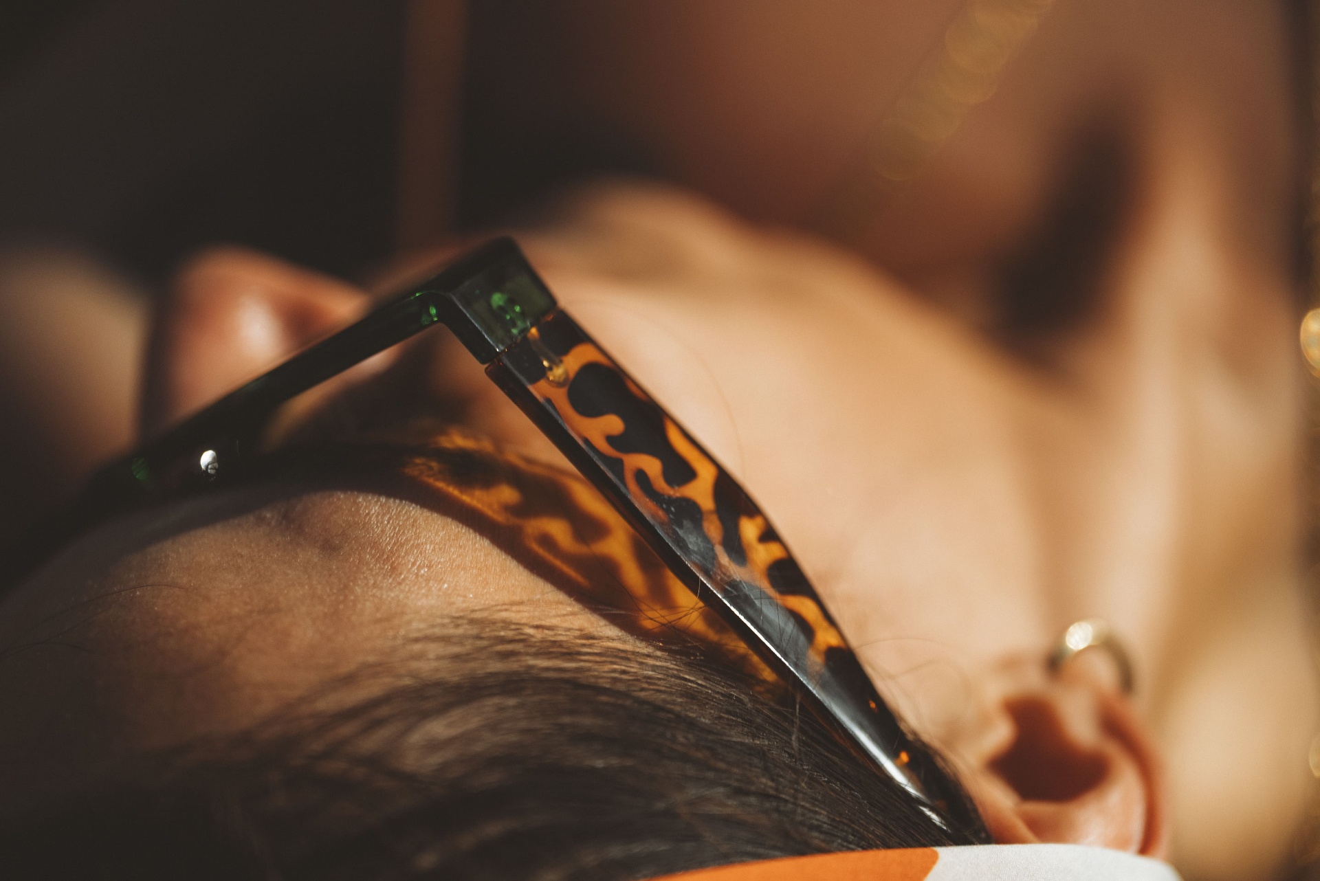 Detalhe de óculos tartaruga em contraluz dourada