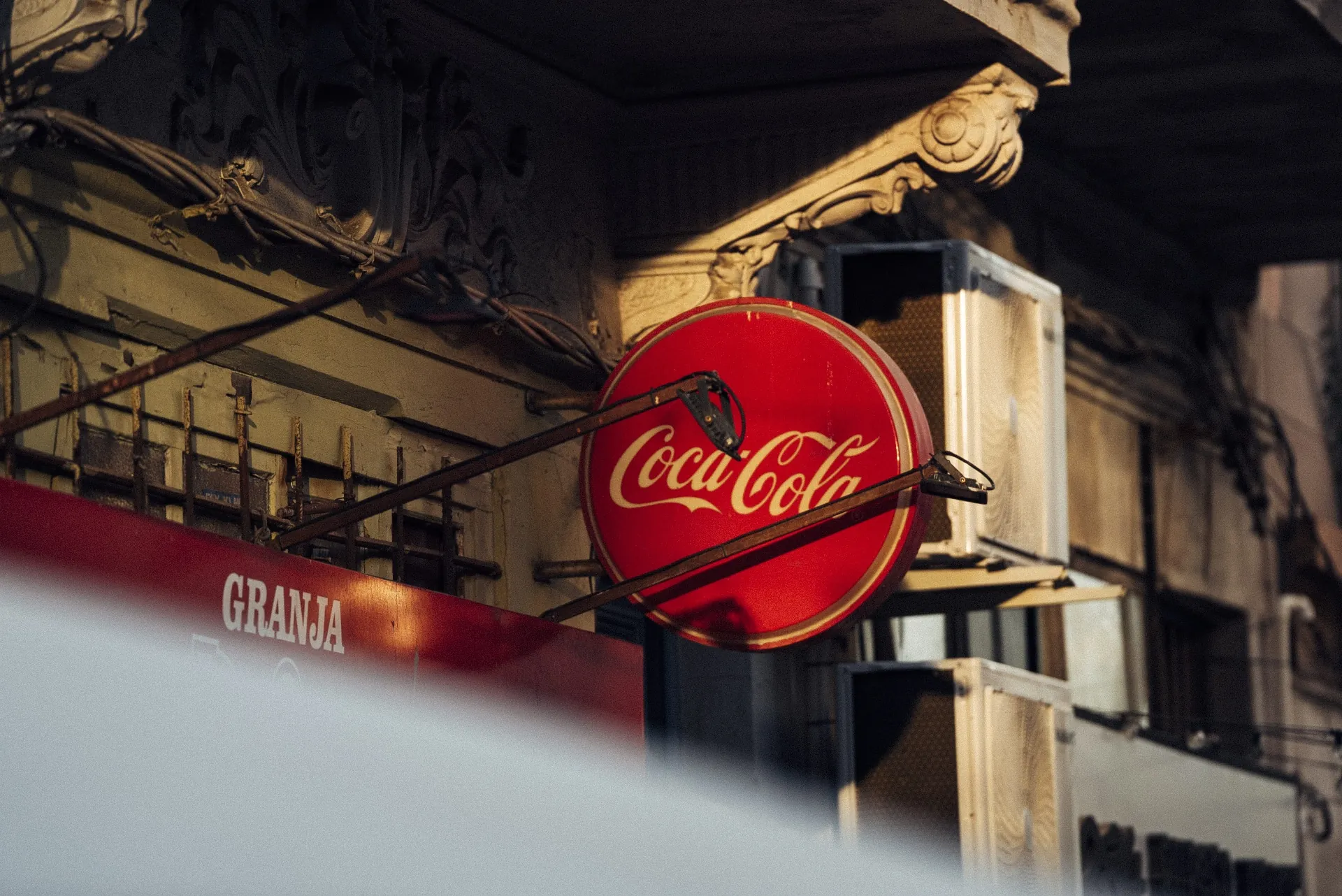 Letreiro Coca-Cola em fachada antiga, com luz quente