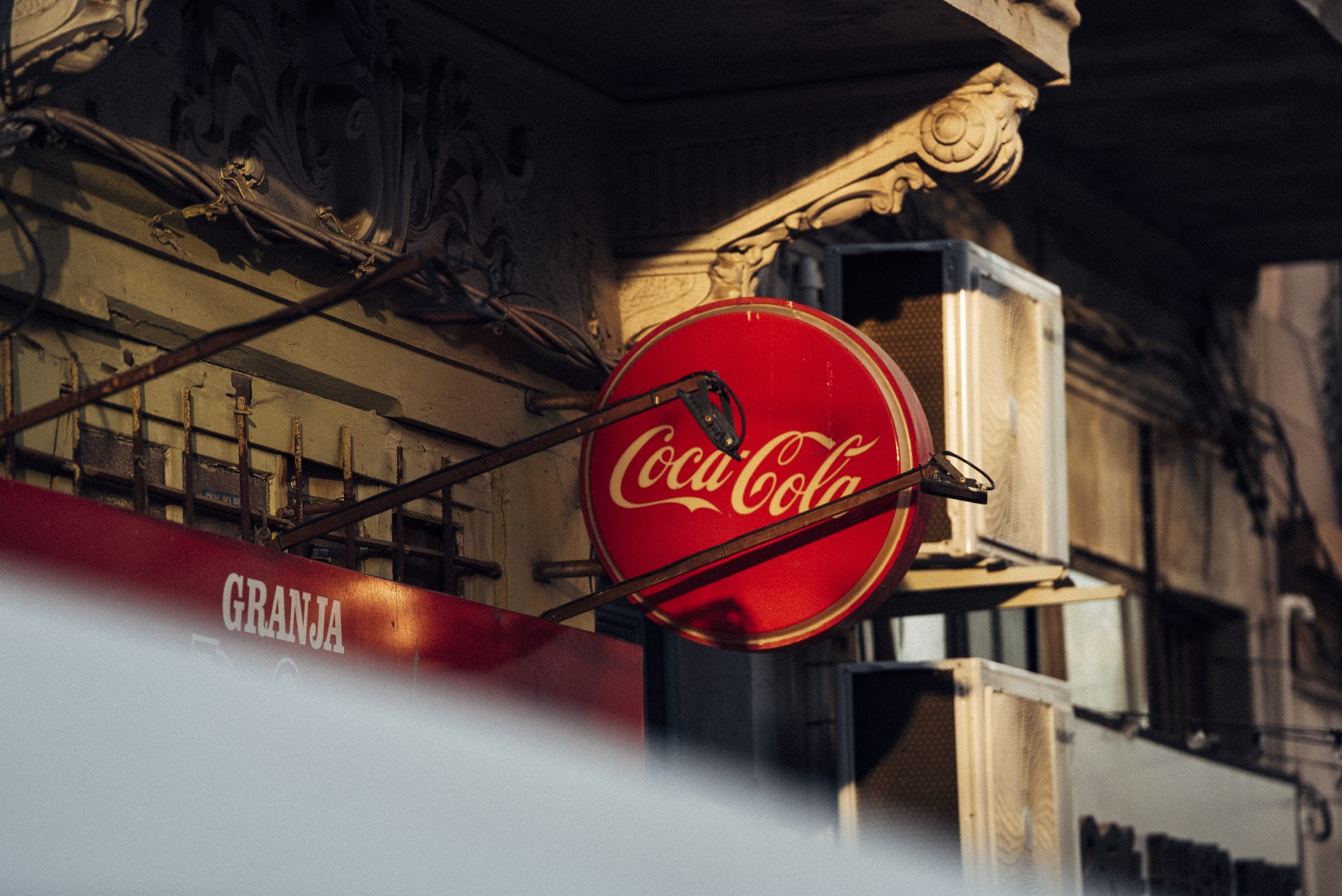 Letreiro Coca-Cola em fachada antiga, com luz quente